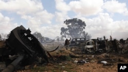 A rebel fighter flashes the victory sign as he walks through the scene of what residents said was a French airstrike against Muammar Gaddafi's forces early on Sunday morning on the southern outskirts of Benghazi in northeastern Libya.