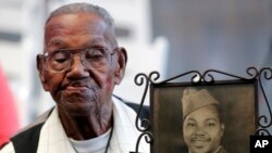 FILE - World War II veteran Lawrence Brooks holds a photo of him taken in 1943, as he celebrates his 110th birthday at the National World War II Museum in New Orleans, on Sept. 12, 2019.