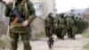 Armed men, believed to be Russian servicemen, walk outside a Ukrainian military base in Perevalnoye, near the Crimean city of Simferopol, March 14, 2014.