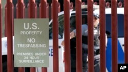 A federal officer watches as DACA supporters protest outside Immigration and Customs Enforcement shortly after U.S. Attorney General Jeff Sessions' announcement that the Deferred Action for Childhood Arrivals (DACA) program will be suspended with a six-month delay, in Phoenix, Sept. 5, 2017. 