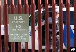 FILE - A federal officer watches as DACA supporters protest outside Immigration and Customs Enforcement offices shortly after U.S. Attorney General Jeff Sessions' announcement that the Deferred Action for Childhood Arrivals program would be suspended with a six-month delay, in Phoenix, Sept. 5, 2017.