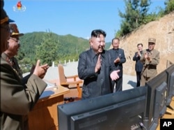 FILE - This image made from video of a news bulletin aired by North Korea's KRT July 4, 2017, shows what was said to be North Korea leader Kim Jung Un, center, applauding after the launch of a Hwasong-14 intercontinental ballistic missile, ICBM, in North Korea.