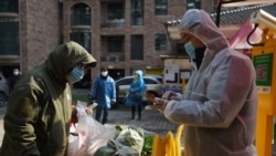 Un residente recoge verduras compradas a través de pedidos grupales en la entrada de un complejo residencial en Wuhan, el epicentro del nuevo brote de coronavirus.