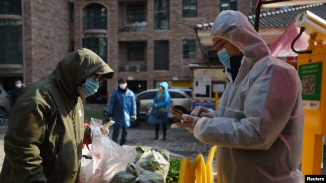 Un residente recoge verduras compradas a través de pedidos grupales en la entrada de un complejo residencial en Wuhan, el epicentro del nuevo brote de coronavirus.