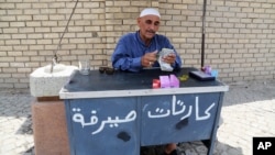 FILE - An Iraqi street currency exchanger counts banknotes in Baghdad, Aug. 8, 2015.