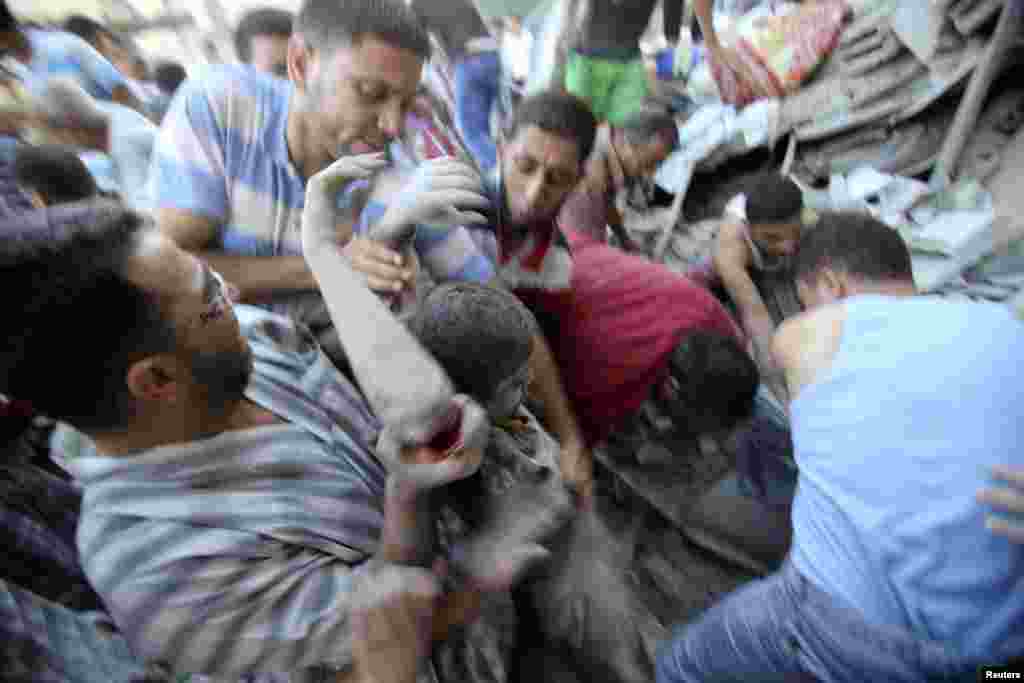 Palestinians rescue Mahmoud al-Ghol from the rubble of a house in Rafah, in the southern Gaza Strip, Aug. 3, 2014.