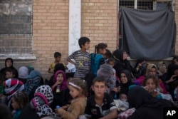 Women and children from Hawija sit outside a Kurdish screening center in Dibis, Iraq, Oct. 3, 2017. Some men, after being separated from the women and children, are investigated for involvement in the Islamic State group.