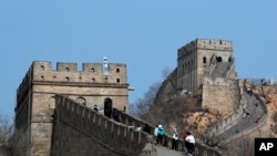 中国北京，在新型冠状病毒爆发后重新开放的八达岭长城上，游客戴着防护口罩行走。随着新的冠状病毒感染病例数量急剧下降，北京的城市动物园和中国长城的部分地区对提前预订的游客重新开放（2020年3月24日）。
