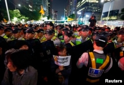 A woman holding a sign stands in front of a barricade of policemen as they march on a street after taking part in a candlelight rally to mourn victims of sunken ferry Sewol and denounce the government's handling of the disaster in central Seoul, South Kor