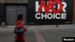 Un femme marche devant un graffiti pro avortement dessiné par l'artiste 'Subset', le 25 mai 2018 à Dublin, Irlande.