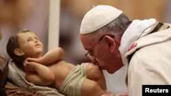 El papa Francisco besa al niño Jesús antes de realizar la Misa de Gallo en la Basílica de San Pedro.