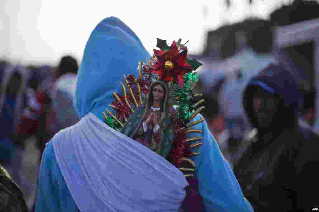 អ្នក​ធ្វើ​ធម្មយាត្រា​ម្នាក់​ស្ពាយ​រូប​ចម្លាក់​ អ្នក​ម្ដាយ​ Guadalupe នៅ​ក្នុង​ពិធី​ប្រារព្ធ​ប្រចាំ​ឆ្នាំ​នៅ​ប្រាសាទ&nbsp;Basilica of Guadalupe ក្នុងទីក្រុង​​ម៉ិកស៊ីកូ។