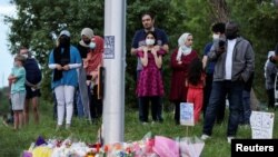 People gather at a makeshift memorial at the fatal crime scene where a man driving a pickup truck jumped the curb and ran over a Muslim family in what police say was a deliberately targeted anti-Islamic hate crime, in London, Ontario, Canada June 7, 2021. REUTERS/Carlos Osorio