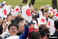 Warga melambaikan bendera Jepang saat menunggu Kaisar Naruhito di luar Istana Kekaisaran di Tokyo, Jepang, 1 Mei 2019.