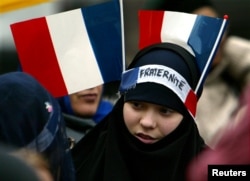 Seorang gadis Muslim muda dengan dua bendera Prancis dan ikat kepala bertuliskan "Persaudaraan." (Foto: Reuters)