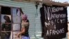 FILE - A man replaces a broken window at a tavern in Philippi township, on the outskirts of Cape Town, South Africa, Monday, April 20, 2015.
