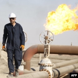 A worker walks on oil pipe at West Qurna oilfield in Iraq's southern province of Basra November 28, 2010. U.S. oil major ExxonMobil and its partners have awarded a contract to oil services firm Schlumberger Ltd to drill 10 wells in Iraq's West Qurna Phase