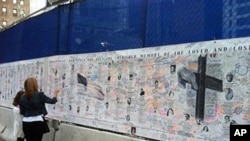 一位女士在世贸中心旧址纪念圆外布满姓名和照片的墙壁上寻找亲人名字