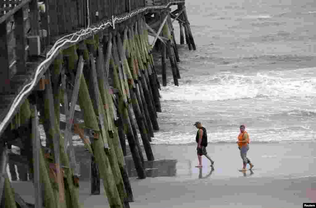 Para turis berjalan-jalan di Pantai Surfside, South Carolina, sebelum hujan dan bagian luar Badai Arthur bergerak mendekat (3/7).&nbsp;(Reuters/Randall Hill)