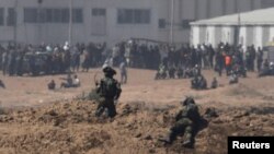 以色列士兵在加沙地带的以色列一边注视着巴勒斯坦抗议者。 （2018年5月14日）