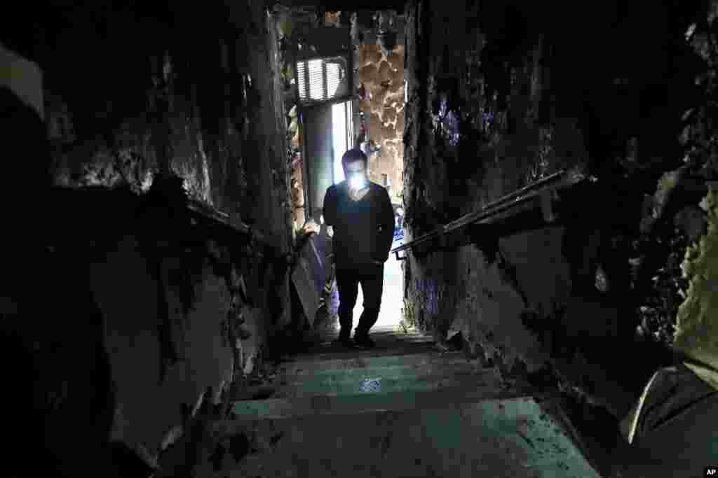 A man lights his mobile phone as he films the burned stairs of Tripoli municipality that was set on fire by protesters during a demonstration against worsening living conditions and severe coronavirus lockdown measures, in Tripoli, Lebanon.