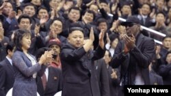 북한의 김정은 국방위원회 제1위원장이 28일 평양에서 열린 미국의 묘기 농구단 시범 경기장에 참석, 방북 중인 전 미국프로농구(NBA) 선수 데니스 로드먼과 함께 관중들에게 인사하고 있다. 왼쪽은 부인 리설주.