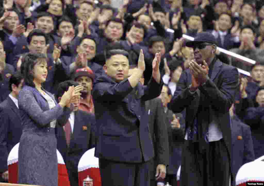 북한의 김정은 국방위원회 제1위원장이 28일 평양에서 열린 미국의 묘기 농구단 시범 경기장에 참석, 방북 중인 전 미국프로농구(NBA) 선수 데니스 로드먼과 함께 관중들에게 인사하고 있다. 왼쪽은 부인 리설주.