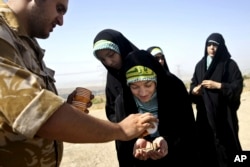 FILE - A female member of the Iranian Basij paramilitary militia, affiliated to the Revolutionary Guard, receives bullets during a training session in Tehran, Iran, Aug. 22, 2013.