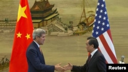 ລມຕ ຕ່າງປະເທດສະຫະລັດ ທ່ານ John Kerry (ຊ້າຍ) ແລະ ລມຕ ຕ່າງປງະເທດຈີນ ທ່ານ Wang Yi ຈັບມືກັນ ຫຼັງຈາກ ກອງປະຊຸມຖະແຫຼງຂ່າວ ທີ່ກະຊວງຕ່າງປະເທດຈີນ ຢູ່ປັກກິ່ງ (16 ພຶດສະພາ 2015) 