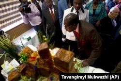 Former President Robert Mugabe blows out the candles on his birthday cake as he marks his 93rd birthday at his offices in Harare, Feb. 21, 2017.