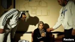 Suhad al-Katib, a Palestinian woman patient who suffers cancer holds a glass of water as she sits at her house after she was not allowed to enter Israel, in Gaza City, Feb. 12, 2014. 