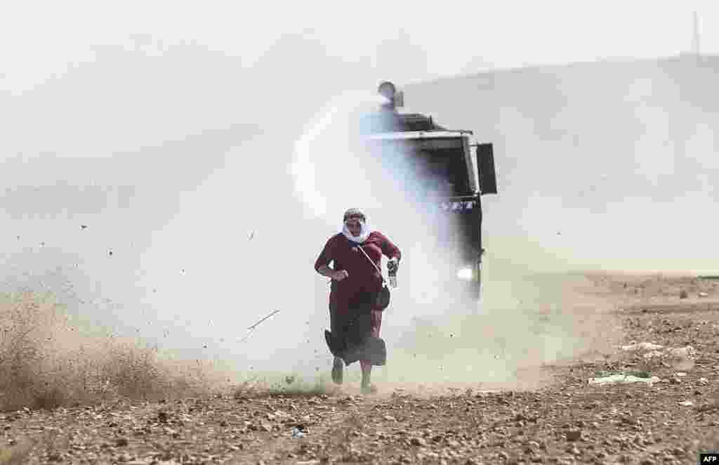 A Kurdish woman runs away from a water cannon near the Syrian border after Turkish authorities temporarily closed the border at the southeastern town of Suruc in Sanliurfa province.