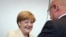 German Chancellor Angela Merkel (L) twinkles to the parliamentary group leader of the conservative Christian Democratic Union (CDU) Volker Kauder ahead of the faction meeting of CDU and CSU in Berlin.