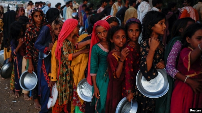 Flood victims gather to receive food handout in a camp, following rains and floods during the monsoon season in Sehwan, Pakistan September 15, 2022. (REUTERS/Akhtar Soomro)