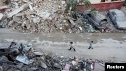 Anak-anak tampak berjalan di salah satu area yang hancur di Kota Tyre, Lebanon, pada 28 November 2024. (Foto: Reuters/Aziz Taher)