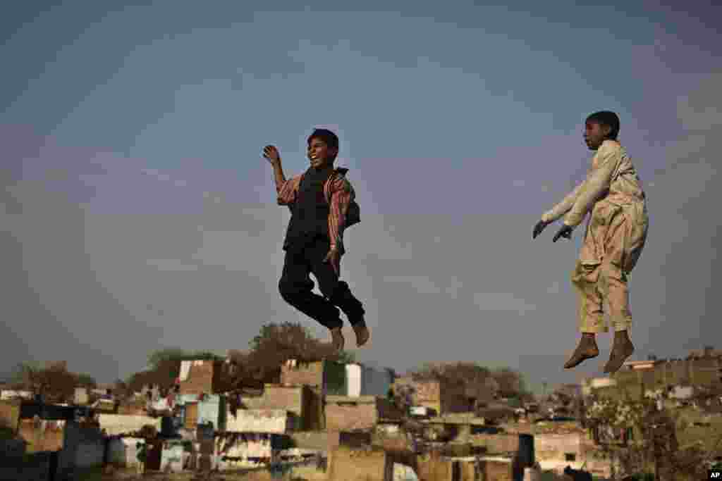 Des jeunes garçons pakistanais en train de sauter sur un trampoline, dans un parc de divertissement de fortune mis en place dans un quartier chrétien pour les vacances de Noël, à Islamabad, au Pakistan, mardi 23 décembre 2014