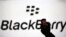 A man silhouetted against a video screen with the Blackberry logo poses with a Blackberry Q10 in this photo illustration taken in the central Bosnian town of Zenica, September 21, 2013.