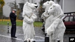 Manifestantes disfrazados de osos polares conversan luego de una protesta bajo la mirada de un policía en una calle cercana a la Conferencia COP 23 Fiji de la ONU para el Cambio Climático, en Bonn, Alemania. Nov. 11, 2017.