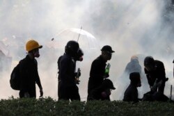 FILE - Pro-democracy protesters react as police fire tear gas at Hong Kong Polytechnic University in Hong Kong, Nov. 17, 2019.