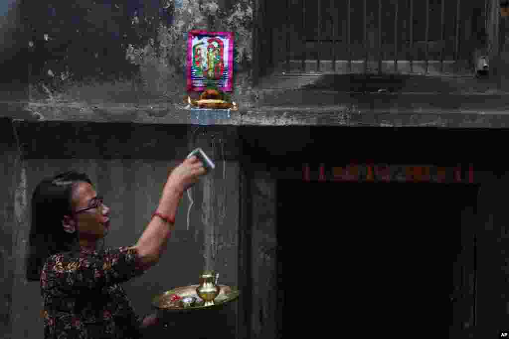 A Nepalese woman puts a traditional painting above her house door during Naag Panchami festival in Bhaktapur, Nepal, Aug. 5, 2019. 