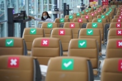 FILE - A tourist wearing a protective mask sits on a social distancing seat as she waits for her flight at Bangkok's Suvarnabhumi International airport amid the spread of the coronavirus disease, in Thailand, June 3, 2020.