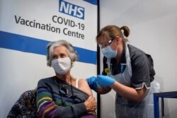 FILE - A woman receives a COVID-19 vaccine jab, at Guy's Hospital, in London, Britain, Dec. 8, 2020.