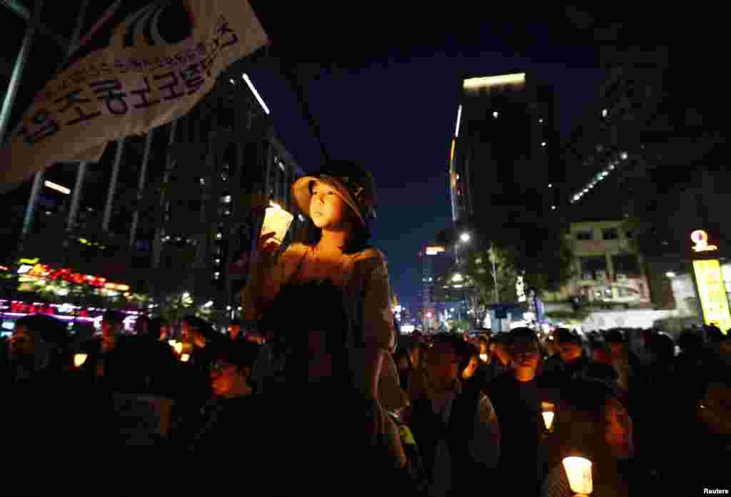 Warga berbaris di jalan setelah mengadakan upacara penyalaan lilin untuk berdoa bagi korban tenggelamnya kapal feri Sewol dan mengecam penanganan bencana itu oleh pemerintah, di pusat kota Seoul (17/5). (Reuters/Kim Hong-Ji)