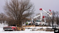 FILE - Utility workers from Xcel Energy tend to power lines near a home destroyed by the Smokehouse Creek fire on Feb. 29, 2024, in Stinnett, Texas. Xcel said on March 7 that its facilities appeared to have played a role in igniting the massive wildfire.