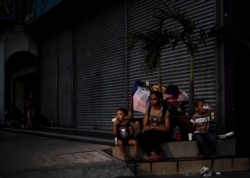 FILE - A homeless woman sits with her children outside closed shops in Kuala Lumpur, Malaysia, Feb. 17, 2016.