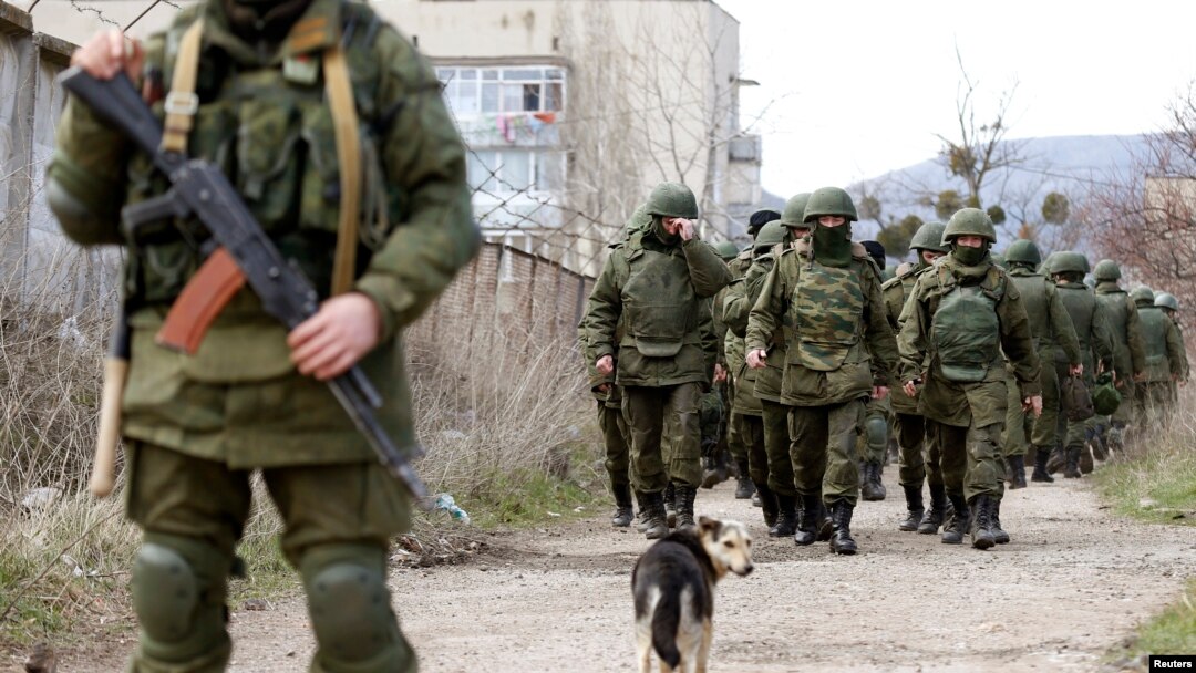 Para pria bersenjata diyakini sebagai orang-orang Rusia berjalan di luar pangkalan militer Ukraina di Perevalnoye, dekat Krimea (14/3).