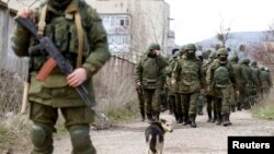 Armed men, believed to be Russian servicemen, walk outside a Ukrainian military base in Perevalnoye, near the Crimean city of Simferopol, March 14, 2014.