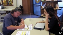 FILE - Molly McGrath, who works for VoteRiders to help people get the required photo identification needed to vote, helps Matthew Kurtz fill out a voter registration form in Madison, Wisconsin, Aug., 31, 2016.