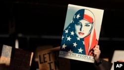 FILE - A protester holds a sign at San Francisco International Airport during a demonstration to denounce President Donald Trump's executive order that bars citizens of seven predominantly Muslim-majority countries from entering the U.S., Jan. 28, 2017.