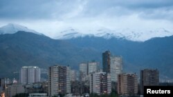 FILE - The Alborz mountain range looms behind Tehran, April 9, 2010. Heavy snow in the region had closed many roads as of Dec. 25, 2020.